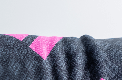 Close-up of dark blue woven fabric with bright pink triangular accents.