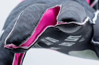 Close-up of a black padded glove with pink lining, highlighting stitching and fabric texture.