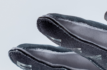 Close-up of black fabric gloves with white seams and a fuzzy interior visible at the edges.