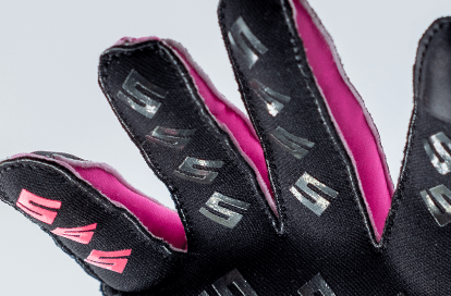 Close-up of a black cycling glove with pink interior, showing textured grip pads on the fingers.
