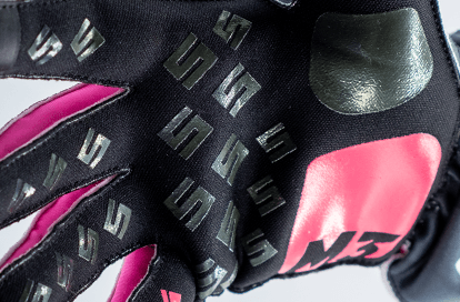 Close-up of a black racing glove with pink accents, covered in small MS logos.
