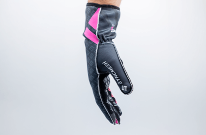Dark gray sport glove with pink panels, hanging mid-air against a light background.