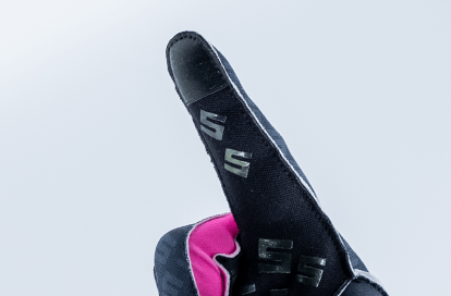 Close-up of a black athletic sneaker with pink interior and an 'S' logo on the side against a light blue gradient background.